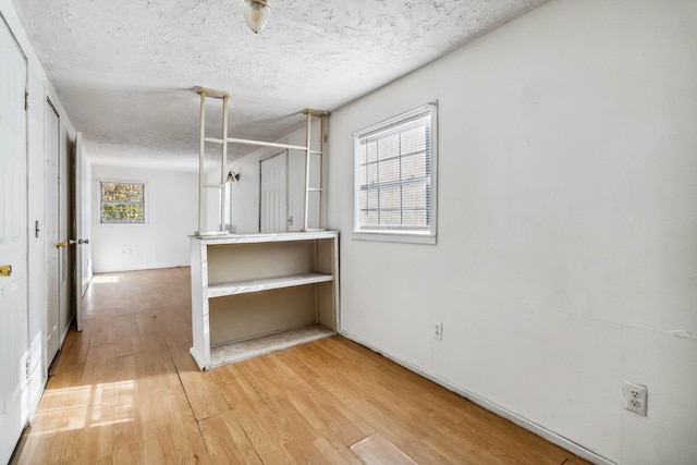 unfurnished room featuring a healthy amount of sunlight, wood-type flooring, and a textured ceiling