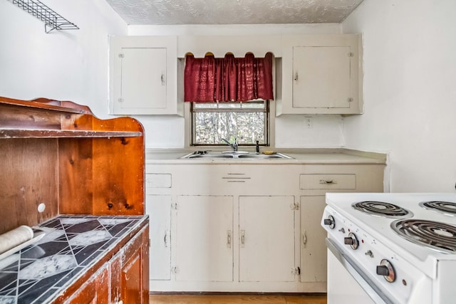 kitchen featuring electric stove, white cabinets, sink, and a textured ceiling