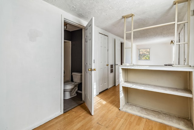 bathroom with wood-type flooring, a textured ceiling, and toilet