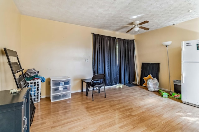 sitting room with ceiling fan, wood-type flooring, and a textured ceiling