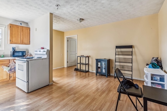 kitchen featuring white electric range oven, light hardwood / wood-style floors, and a textured ceiling