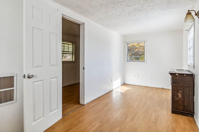 spare room featuring a textured ceiling and light hardwood / wood-style flooring