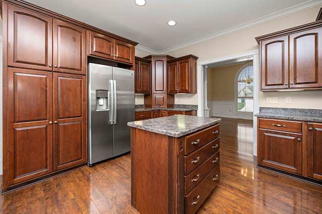 kitchen featuring stainless steel fridge, ornamental molding, dark wood-type flooring, a center island, and dark stone countertops