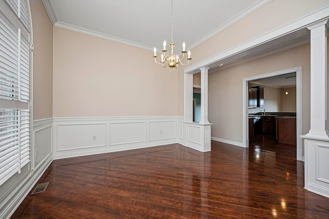 unfurnished dining area featuring a chandelier, ornate columns, crown molding, and dark hardwood / wood-style flooring