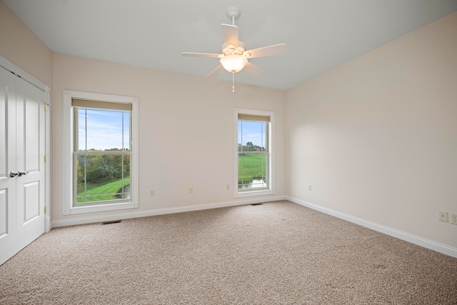 spare room featuring a healthy amount of sunlight, ceiling fan, and carpet floors