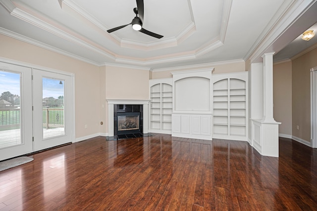 unfurnished living room featuring ceiling fan, dark wood-type flooring, a raised ceiling, decorative columns, and ornamental molding