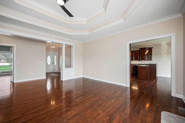 empty room with ceiling fan, sink, a tray ceiling, dark hardwood / wood-style floors, and crown molding