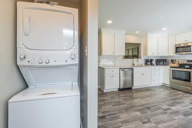 laundry room with hardwood / wood-style floors, stacked washer and dryer, and sink