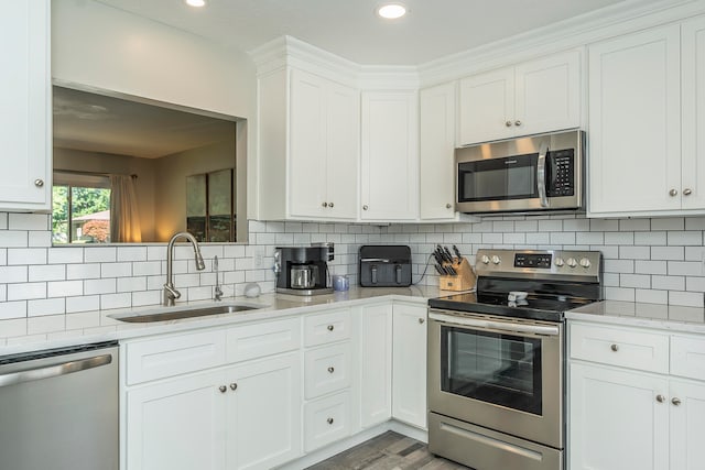 kitchen featuring stainless steel appliances, backsplash, sink, and white cabinetry