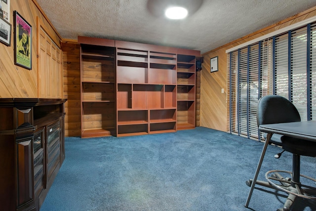 carpeted home office featuring a textured ceiling and wooden walls