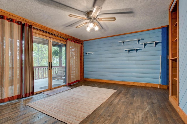 interior space with wood walls, dark hardwood / wood-style flooring, ceiling fan, and a textured ceiling