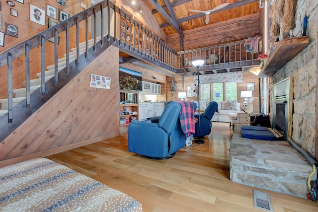 living room with high vaulted ceiling, wooden ceiling, beamed ceiling, hardwood / wood-style floors, and wood walls