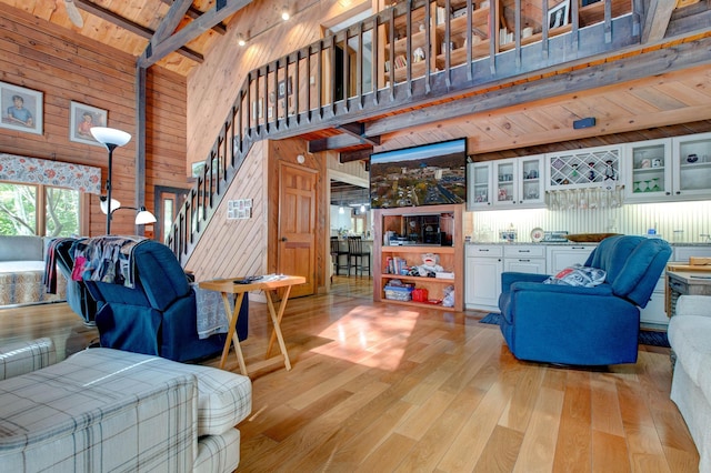 living room featuring wooden walls, high vaulted ceiling, light hardwood / wood-style flooring, wooden ceiling, and beamed ceiling