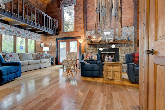 living room with wood walls, a fireplace, high vaulted ceiling, and wood-type flooring