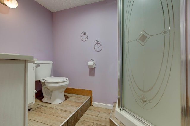 bathroom featuring hardwood / wood-style floors, a textured ceiling, toilet, and walk in shower