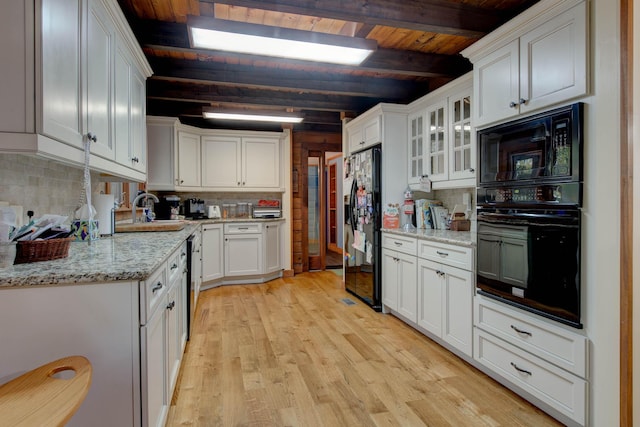 kitchen featuring beam ceiling, white cabinetry, sink, light hardwood / wood-style floors, and black appliances