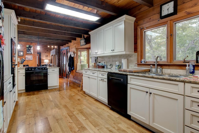 kitchen with wood walls, black appliances, sink, light hardwood / wood-style flooring, and beamed ceiling