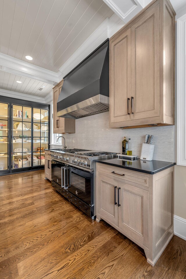 kitchen with wall chimney range hood, beamed ceiling, wood-type flooring, ornamental molding, and double oven range