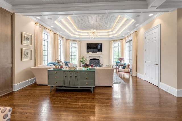 living room featuring ornamental molding, a chandelier, a raised ceiling, and dark hardwood / wood-style flooring