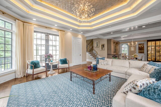 living room featuring crown molding, a raised ceiling, and plenty of natural light