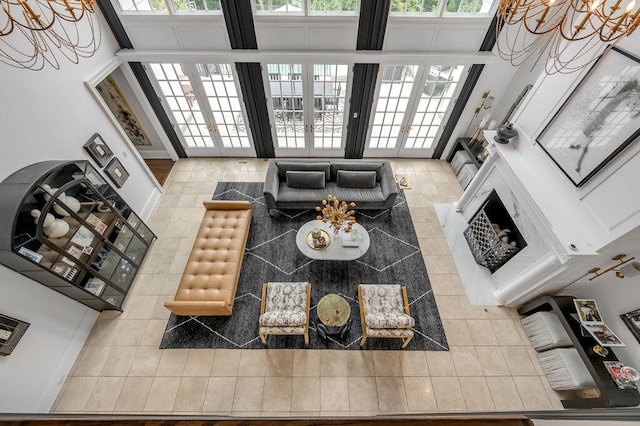 living room with french doors, a towering ceiling, a chandelier, and tile patterned flooring