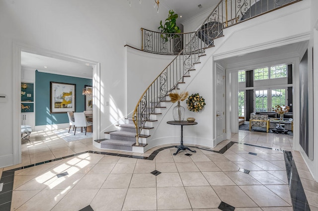 foyer featuring crown molding, tile patterned floors, and a towering ceiling