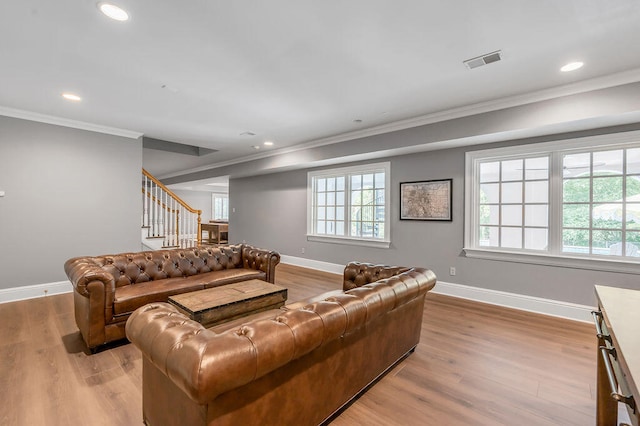 living room featuring a wealth of natural light, crown molding, and light hardwood / wood-style flooring