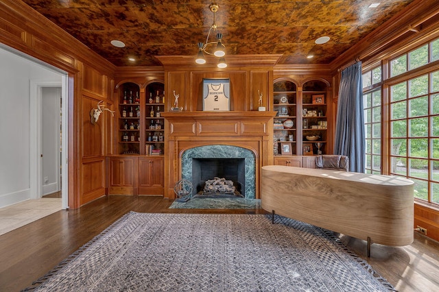 interior space featuring crown molding, built in features, dark hardwood / wood-style floors, and a high end fireplace