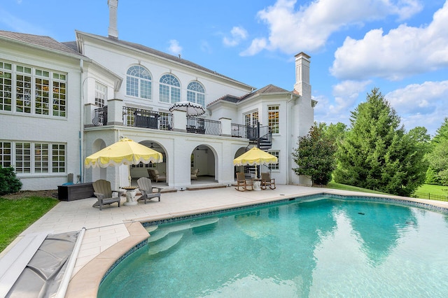 rear view of property featuring a balcony and a patio