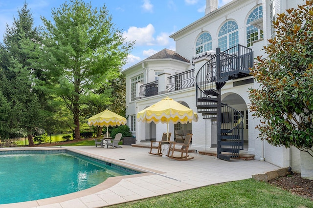 rear view of property featuring a fenced in pool and a patio