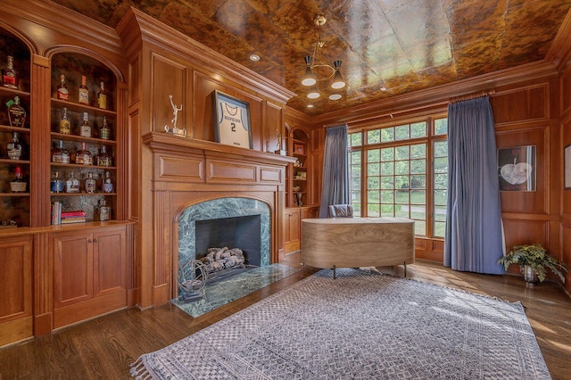 living area featuring a premium fireplace, ornamental molding, built in shelves, and dark hardwood / wood-style flooring