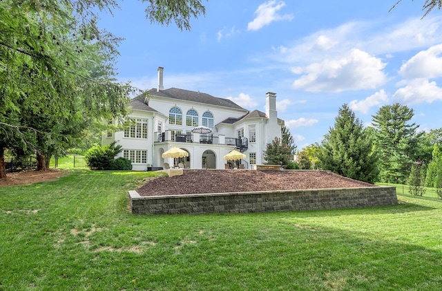 back of house featuring a lawn and a balcony