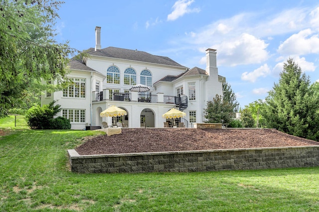 back of property with a yard and a balcony