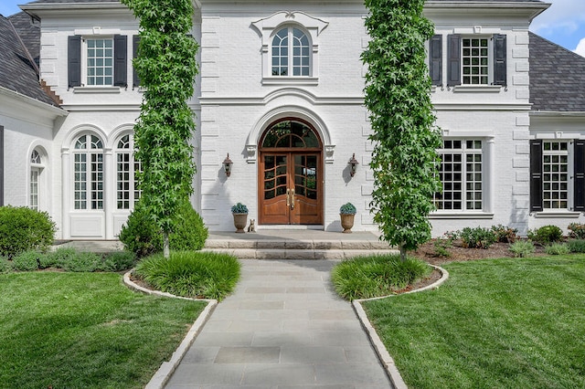 entrance to property with french doors and a lawn