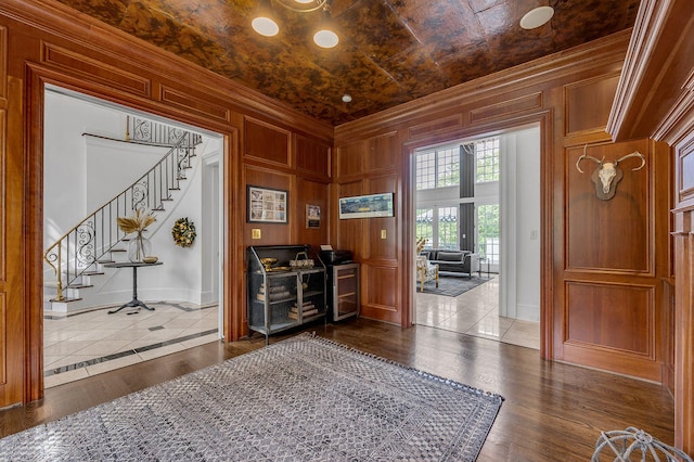 entryway with wood walls, ornamental molding, and hardwood / wood-style flooring