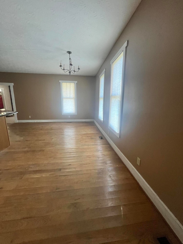 unfurnished dining area with a chandelier and light hardwood / wood-style floors