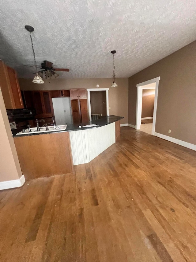 kitchen with a textured ceiling, decorative light fixtures, and hardwood / wood-style floors