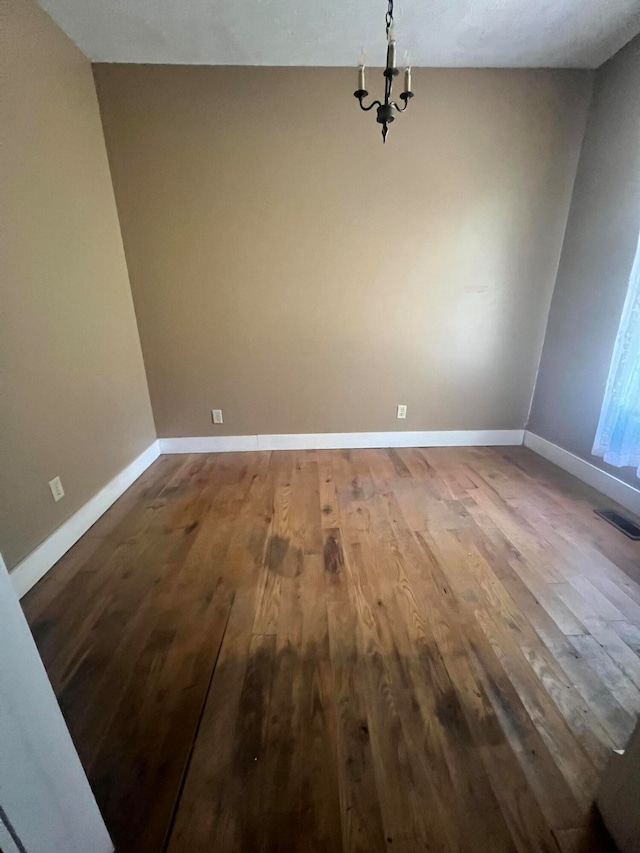 unfurnished dining area featuring wood-type flooring, a textured ceiling, and a chandelier