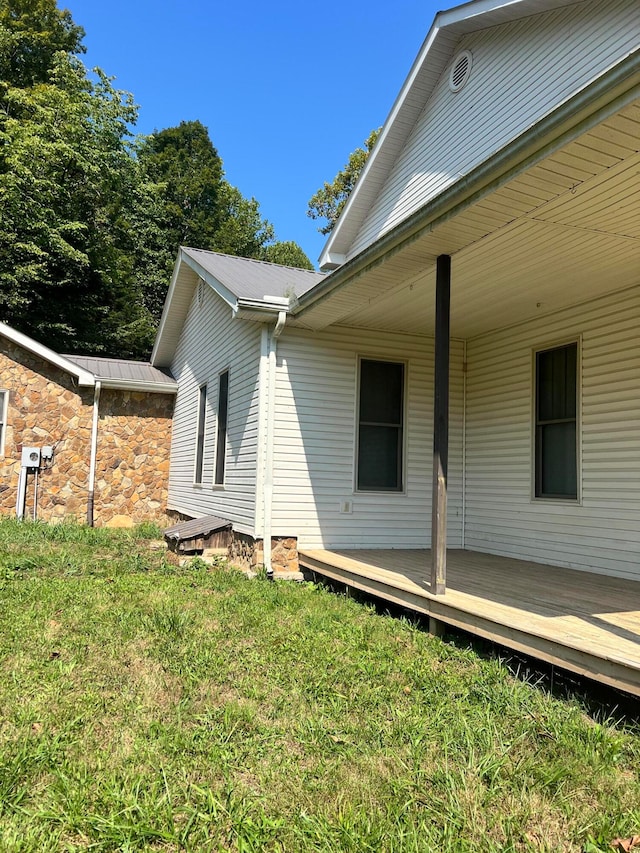 view of property exterior featuring a wooden deck and a lawn