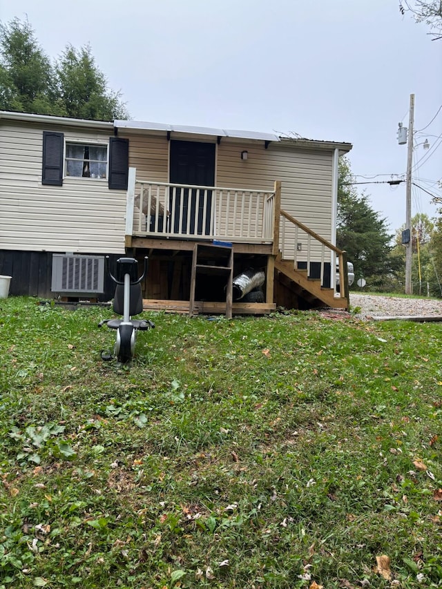 rear view of house featuring a wooden deck, a lawn, and central AC unit