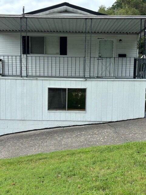 view of side of property with a yard and a balcony