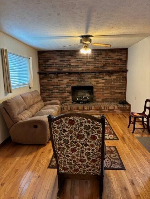 living room with ceiling fan, hardwood / wood-style floors, and a textured ceiling