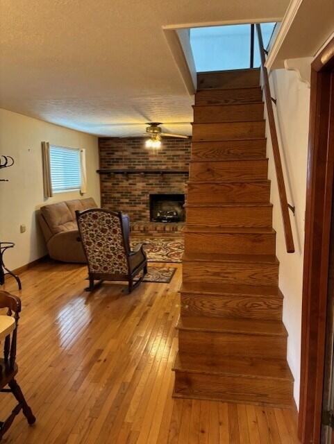 stairs with a skylight, a textured ceiling, a fireplace, and hardwood / wood-style floors