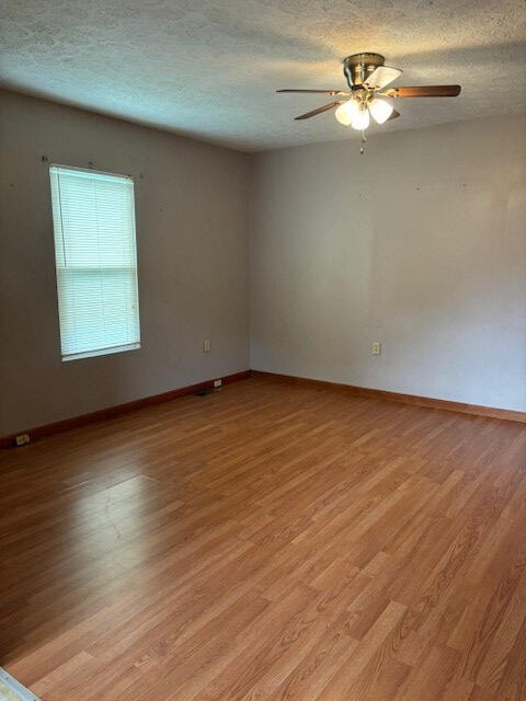 unfurnished room featuring a textured ceiling, ceiling fan, and light hardwood / wood-style flooring