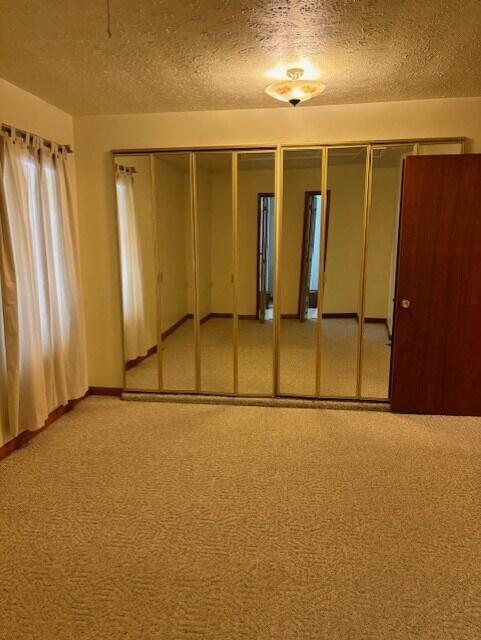 carpeted spare room with a textured ceiling