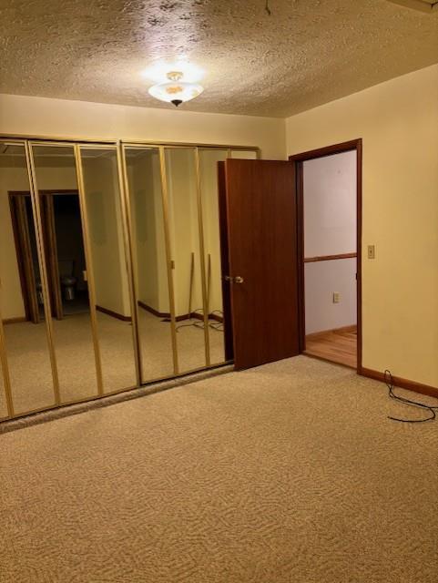 unfurnished bedroom featuring carpet, multiple closets, and a textured ceiling