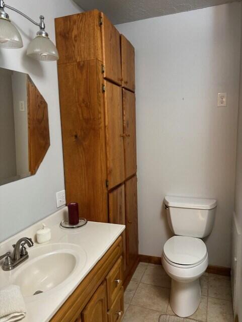 bathroom featuring vanity, toilet, a textured ceiling, and tile patterned floors