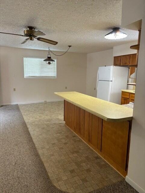 kitchen with ceiling fan, pendant lighting, white refrigerator, carpet, and a textured ceiling