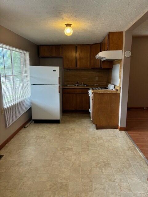 kitchen with white fridge and a textured ceiling