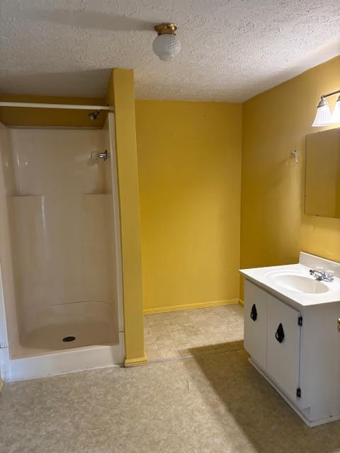 bathroom with vanity, a shower, and a textured ceiling